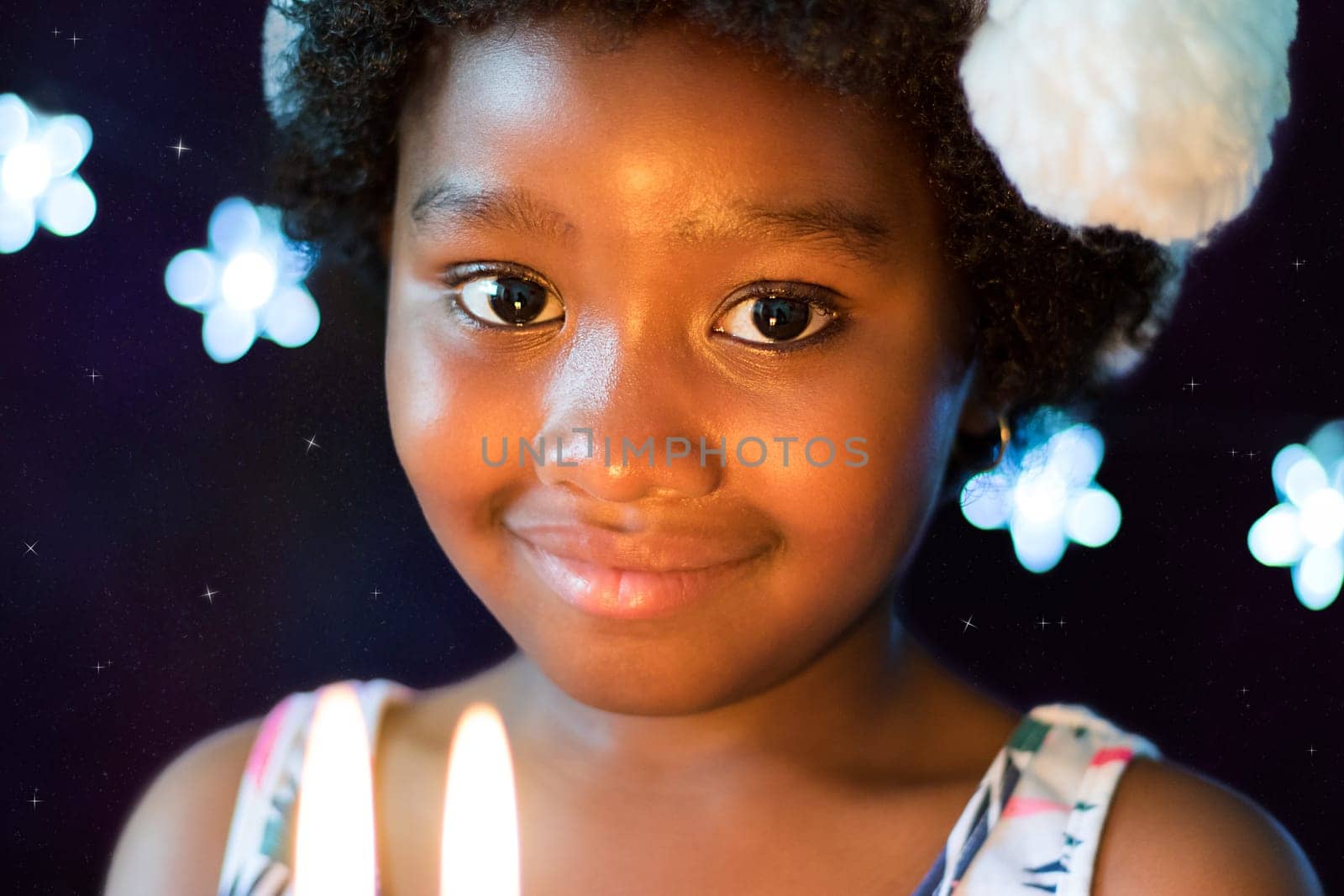 Close up face shot of little african girl at candlelight against glowing star background.