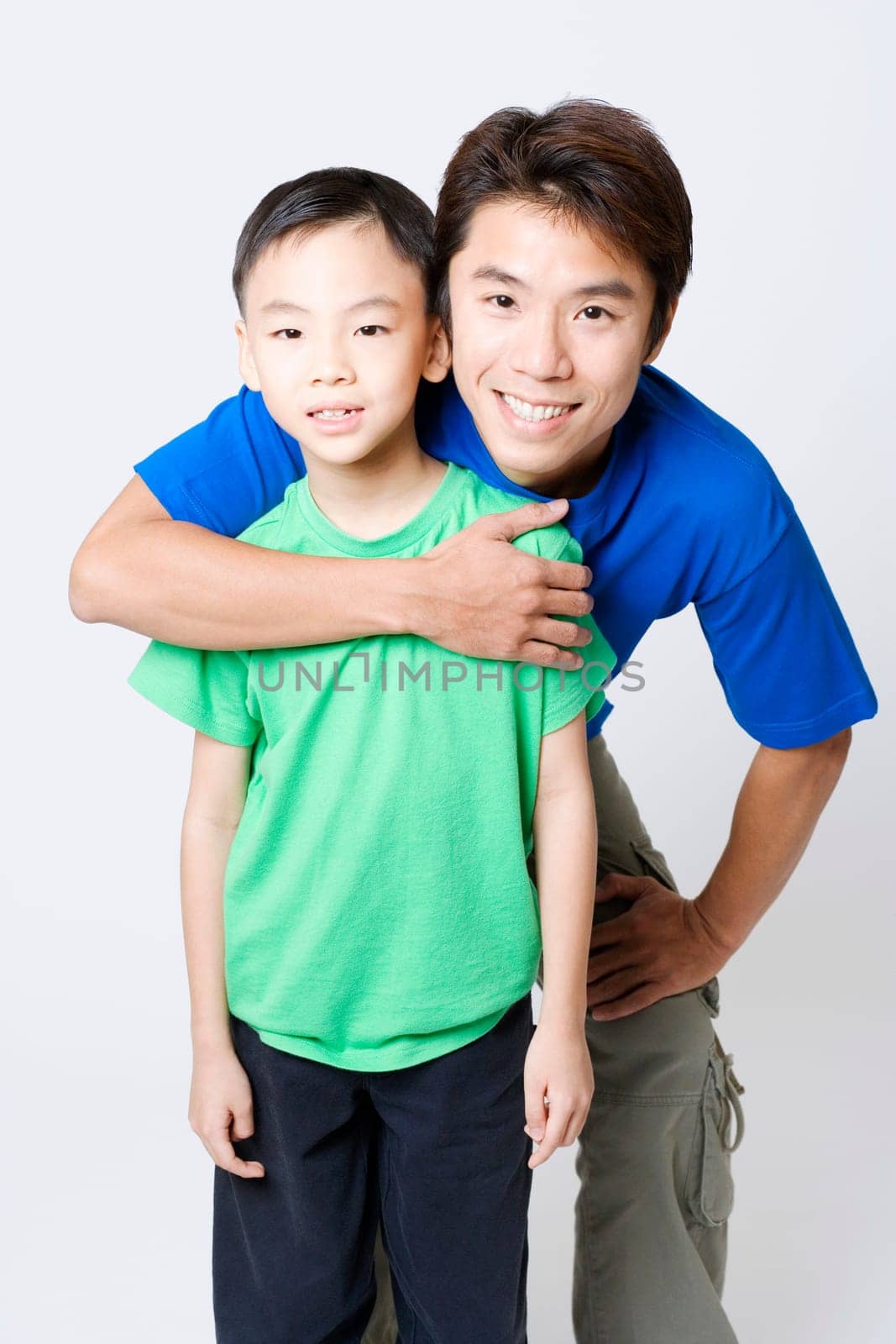 Portrait of a mid adult man hugging his son from behind