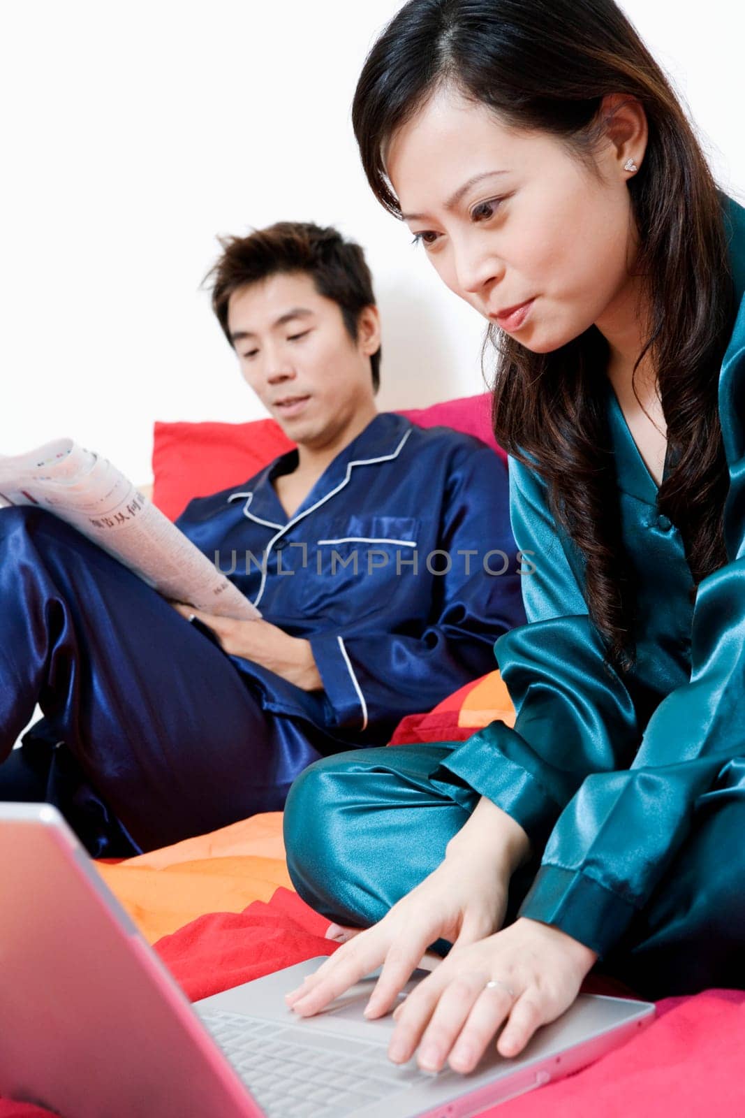 Close-up of a young woman using a laptop and mid adult man holding a newspaper