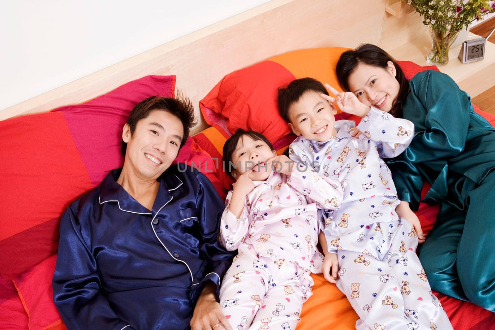 Portrait of two parents lying on the bed with their two children