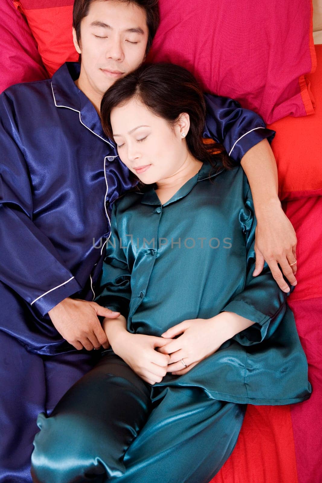 High angle view of a mid adult man and a young woman sleeping on the bed