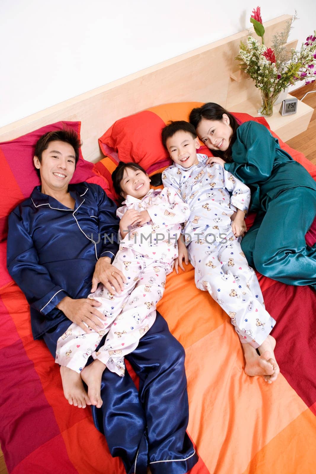 Portrait of two parents lying on the bed with their two children