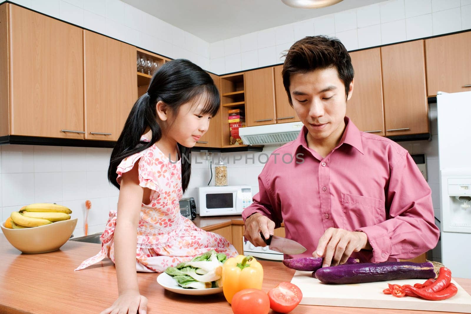 Mid adult man and his daughter cutting vegetables at a kitchen counter