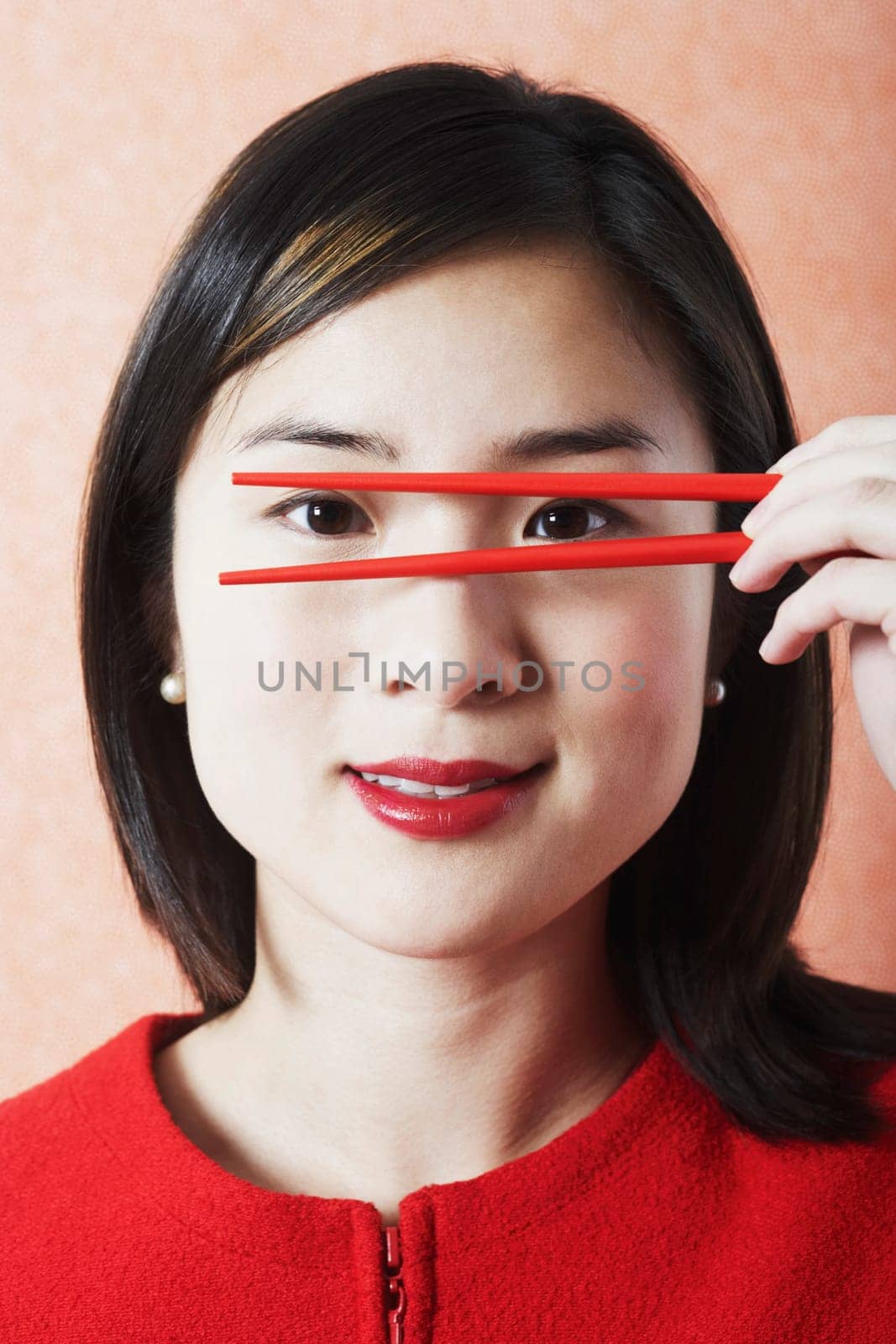 Portrait of a young woman holding chopsticks in front of her face