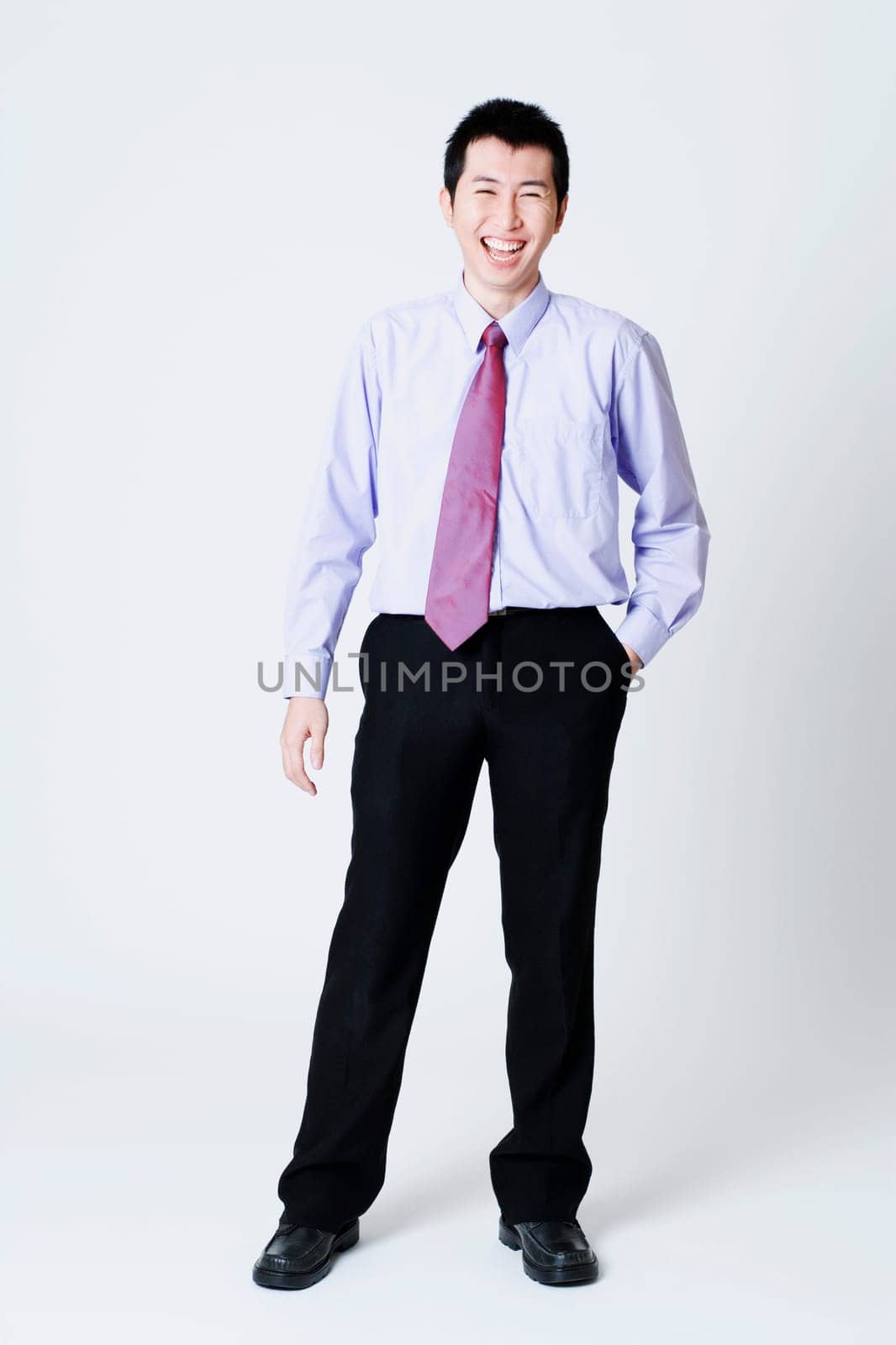 Portrait of a businessman standing with his hands in his pockets by GlowAsia