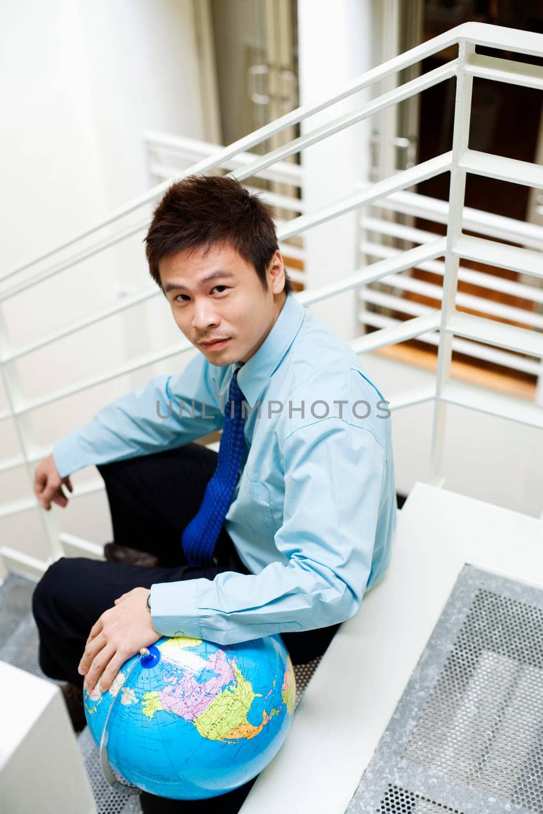 Portrait of a businessman sitting on steps with a globe