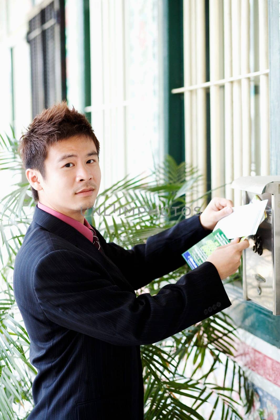 Portrait of a businessman dropping mails into a mailbox
