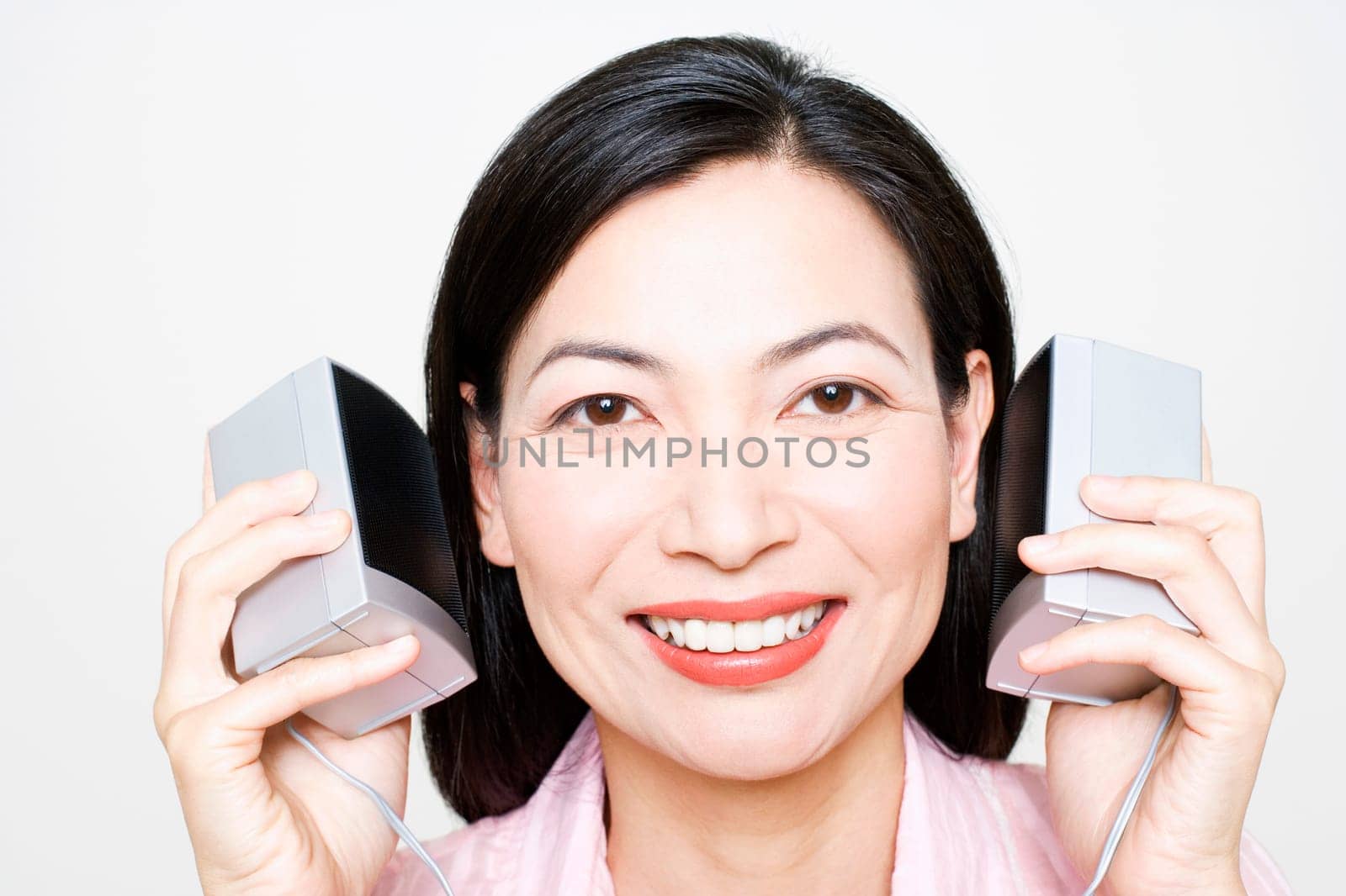 Portrait of a mid adult woman listening to music and holding speakers
