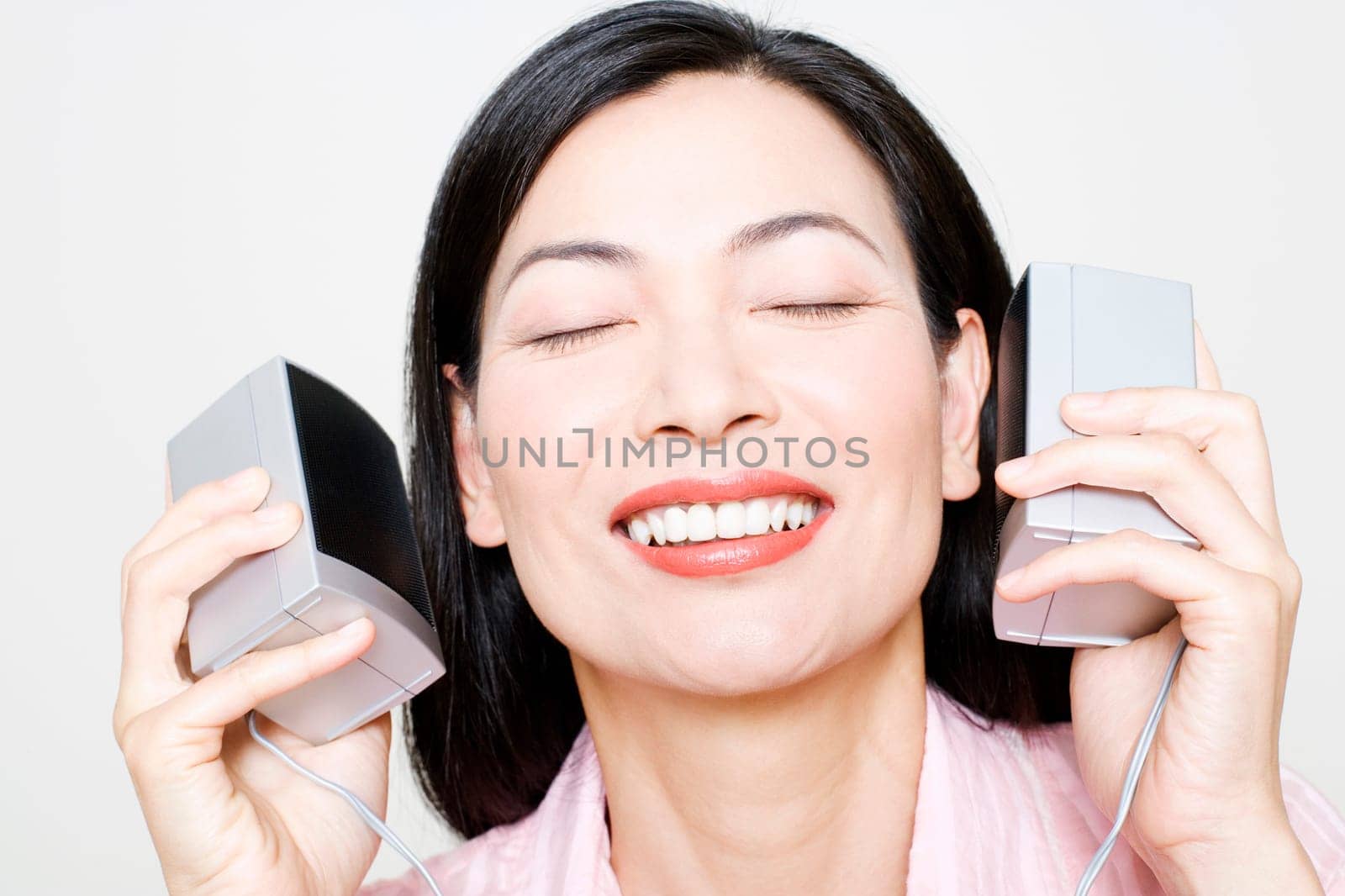 Close-up of a mid adult woman holding speakers upto her ear