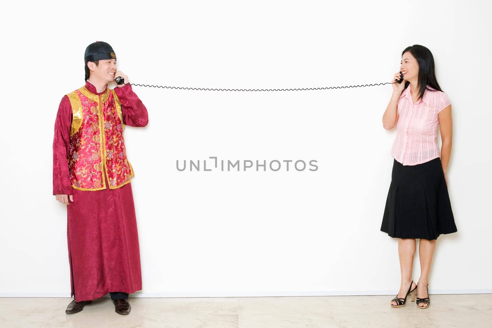 Mid adult woman and a young man talking on telephones
