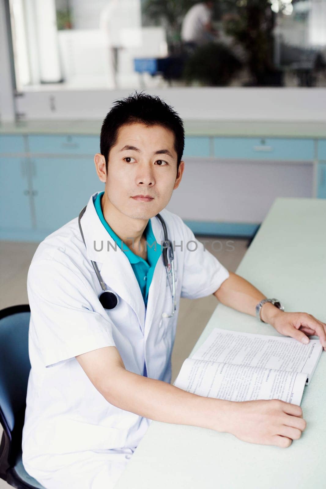 Side profile of a male doctor sitting at the table and holding a book