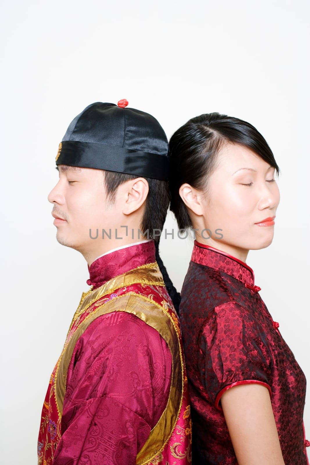 Side profile of a young man and a young woman standing back to back with their eyes closed