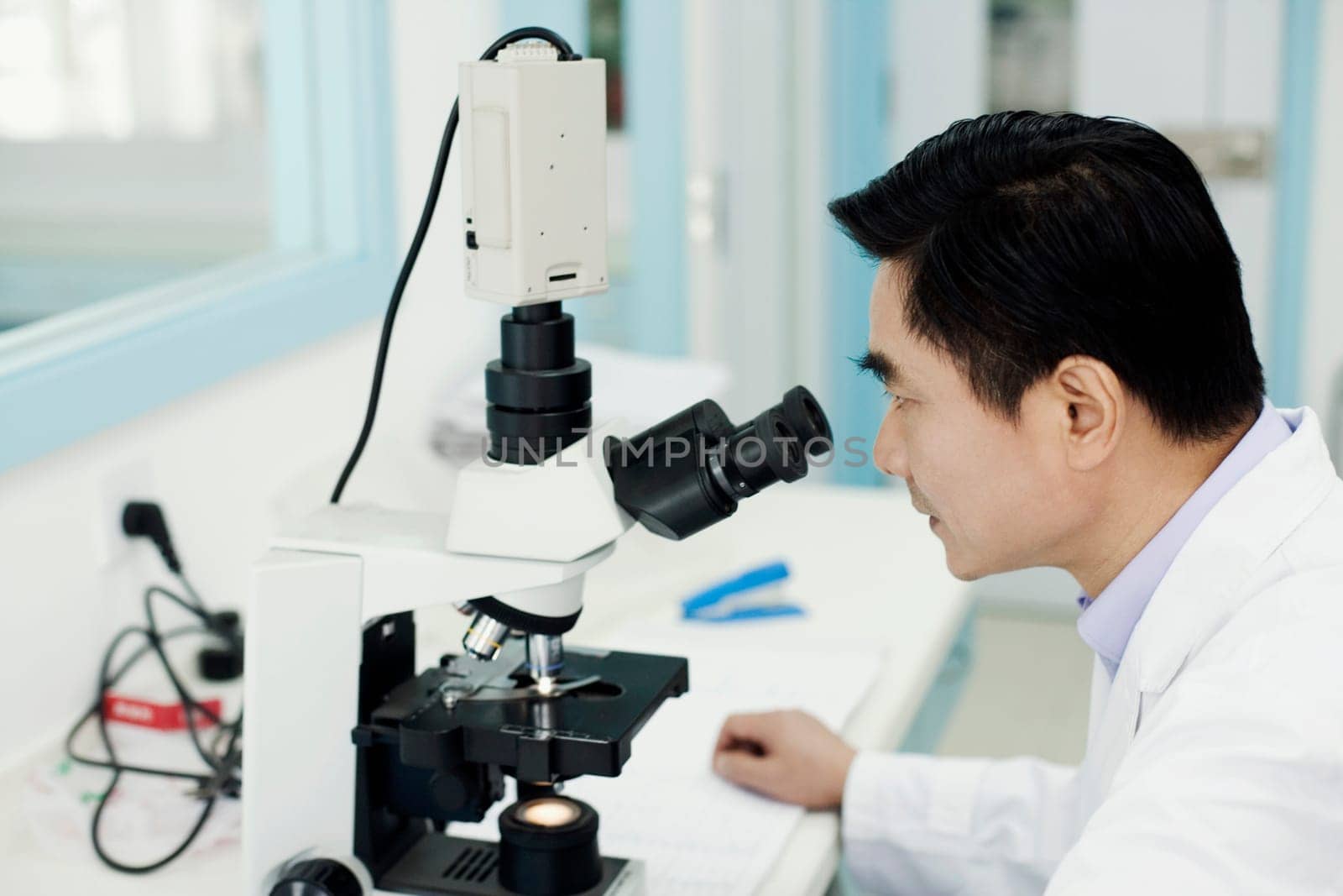 Side profile of a male doctor looking into a microscope