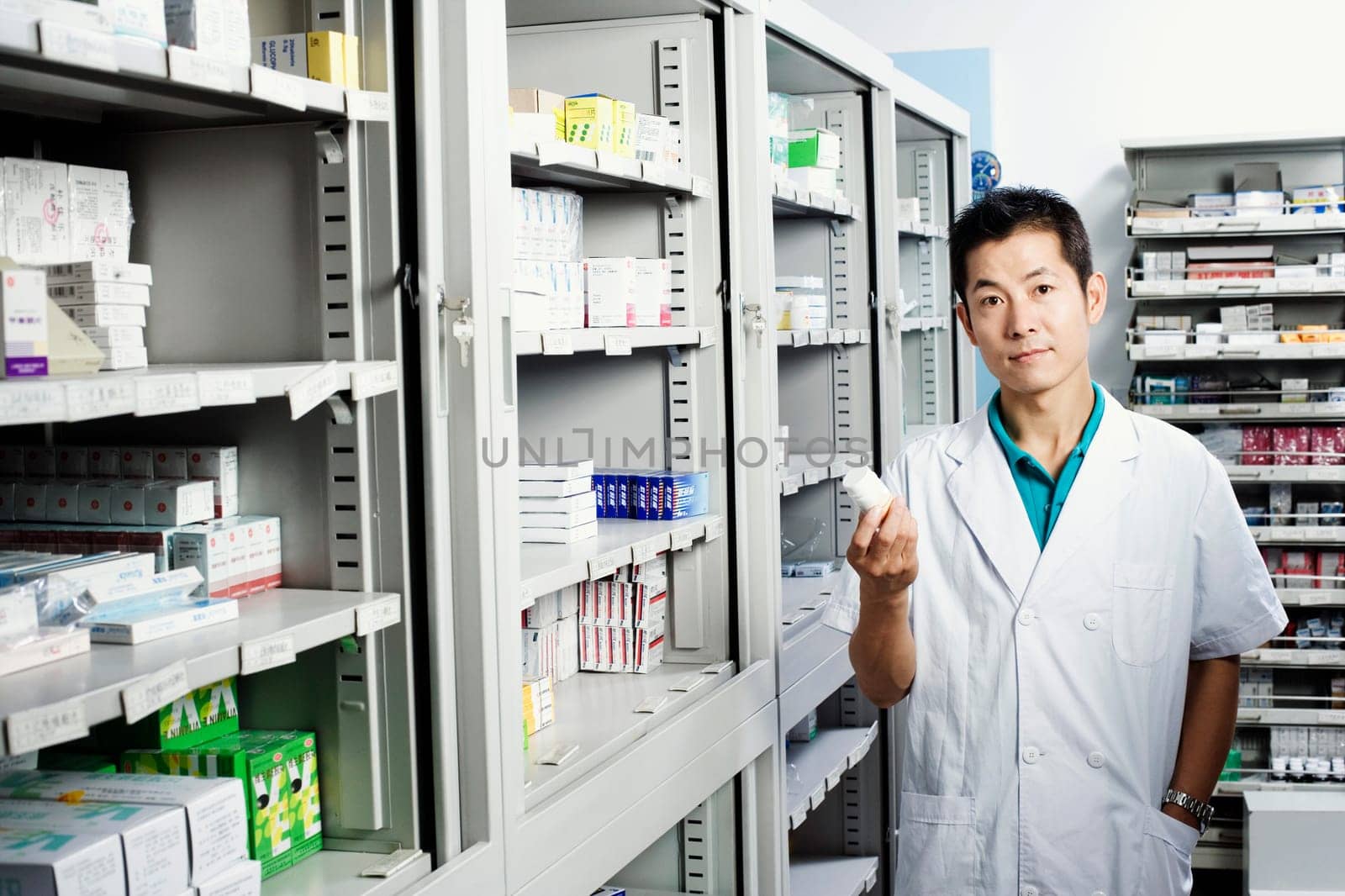 Portrait of a male pharmacist holding a bottle in a store room