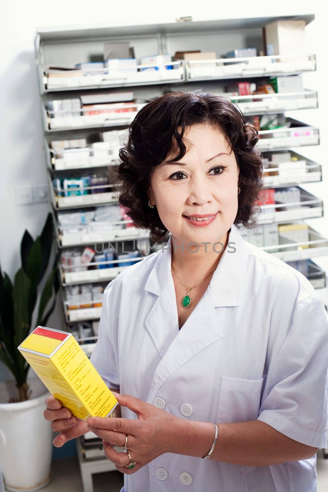 Close-up of a female pharmacist holding medicine in a store room