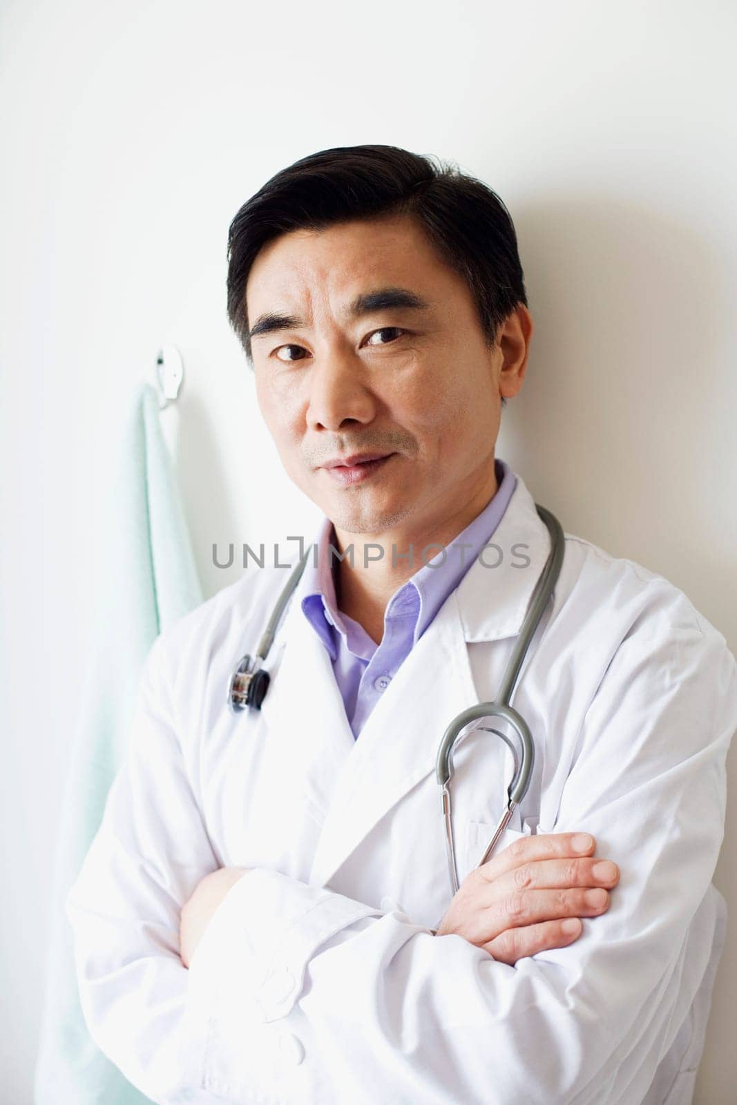 Portrait of a male doctor leaning against a wall