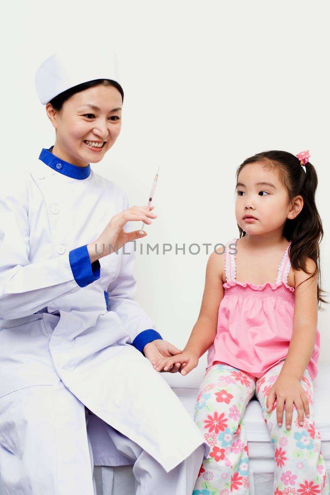 Female nurse holding a girl and a syringe