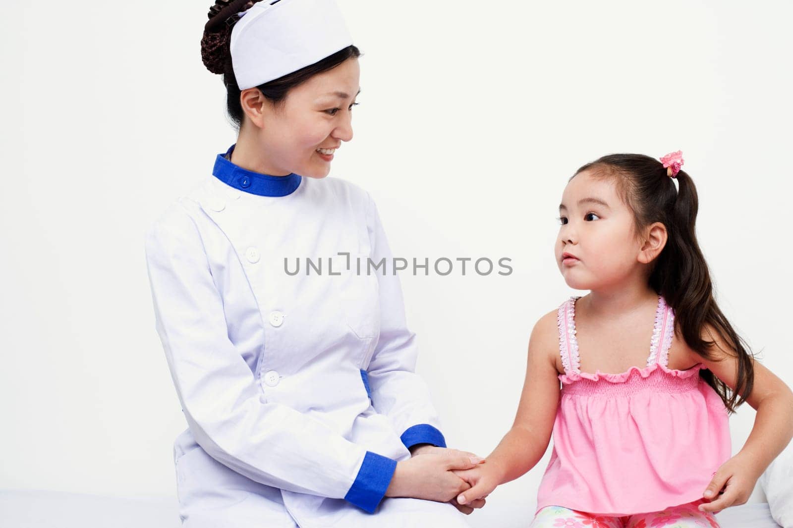 Close-up of a female nurse and a girl child holding hands