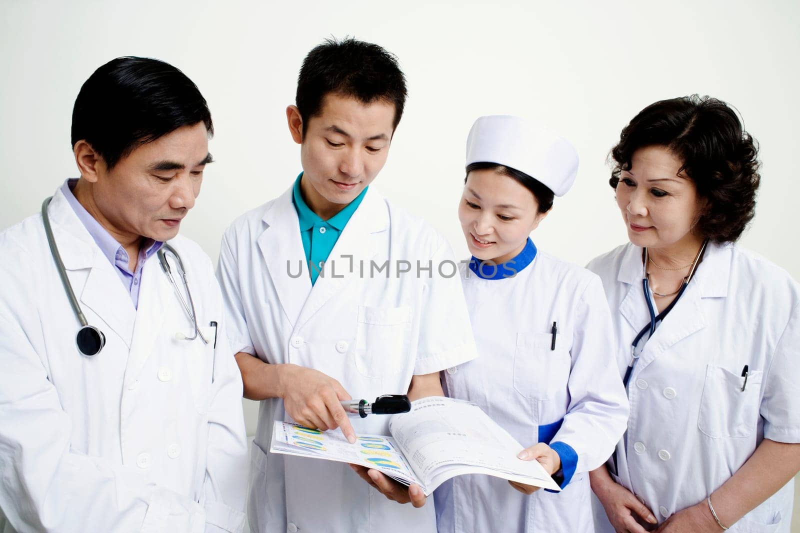 Close-up of two male doctors and a female doctor with a female nurse discussing a report