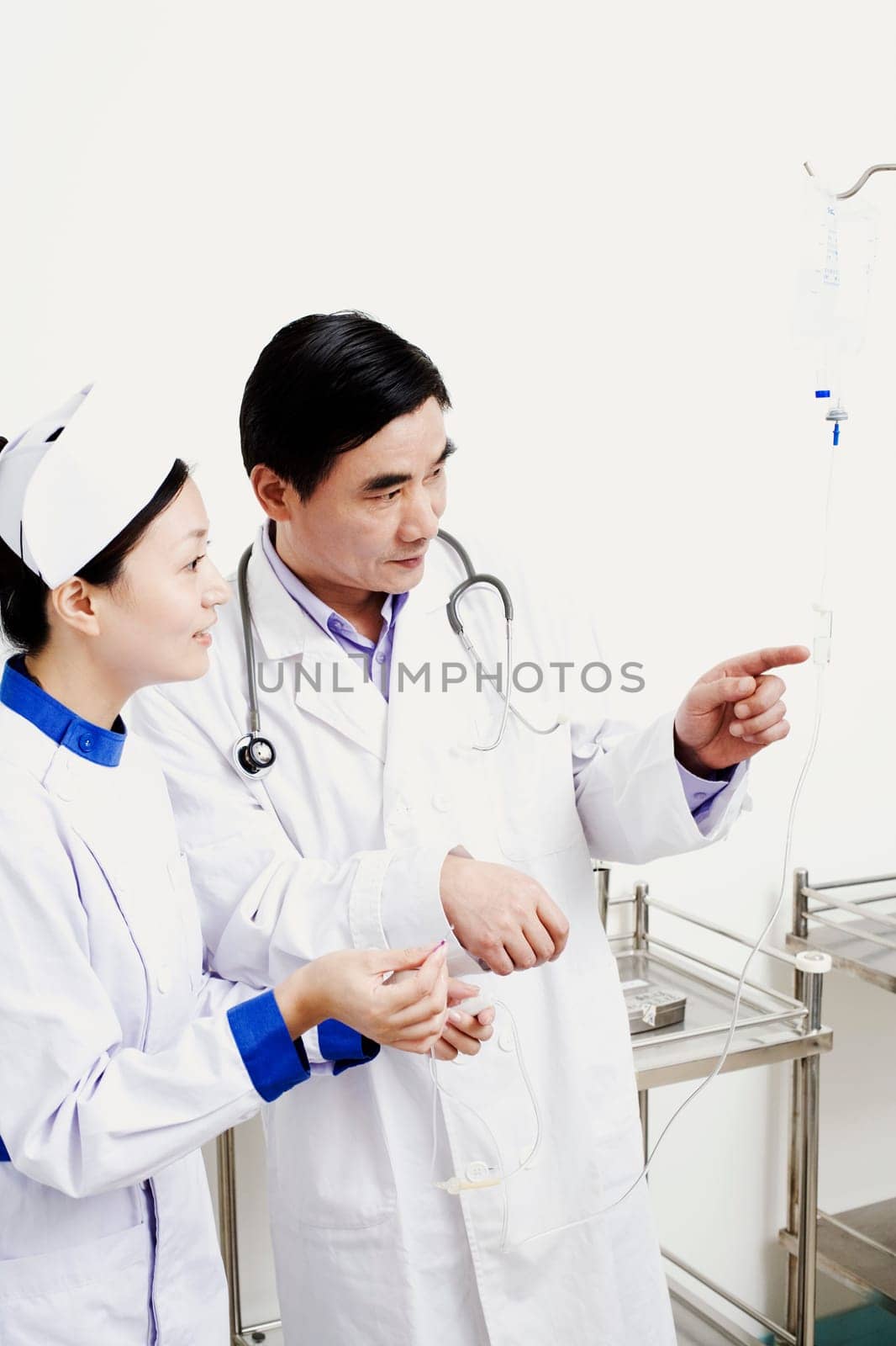 Close-up of a male doctor and a female nurse looking at an iv drip
