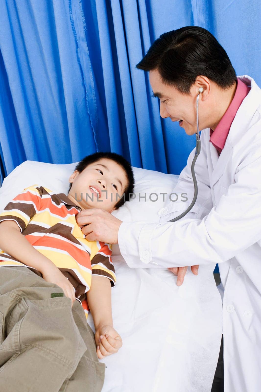 Side profile of a male doctor examining a boy with a stethoscope