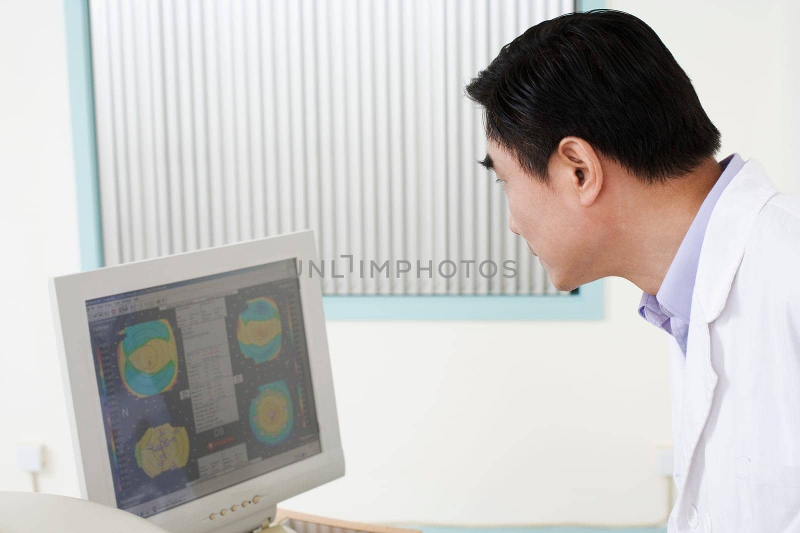 Side profile of a male doctor looking at a computer monitor