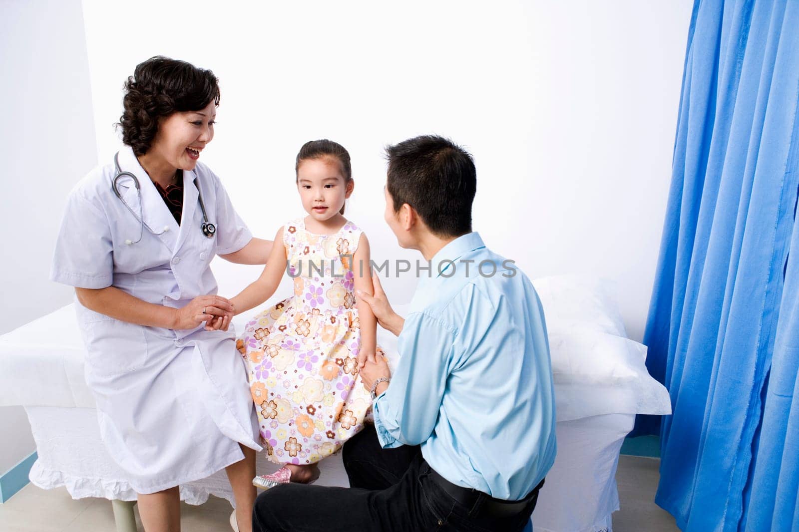 Female doctor and a young man holding a girlŽs hands and sitting