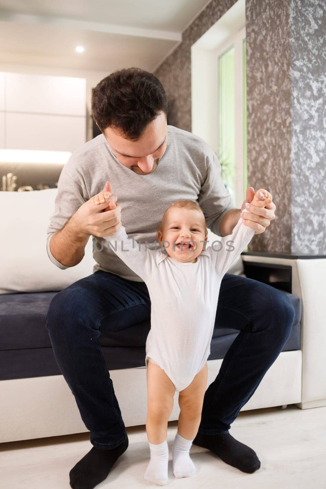 Father teaching a baby to walk in living room at home. First child steps