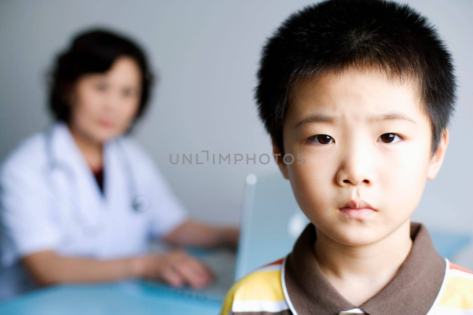 Portrait of a boy with a female doctor working on a laptop in the background