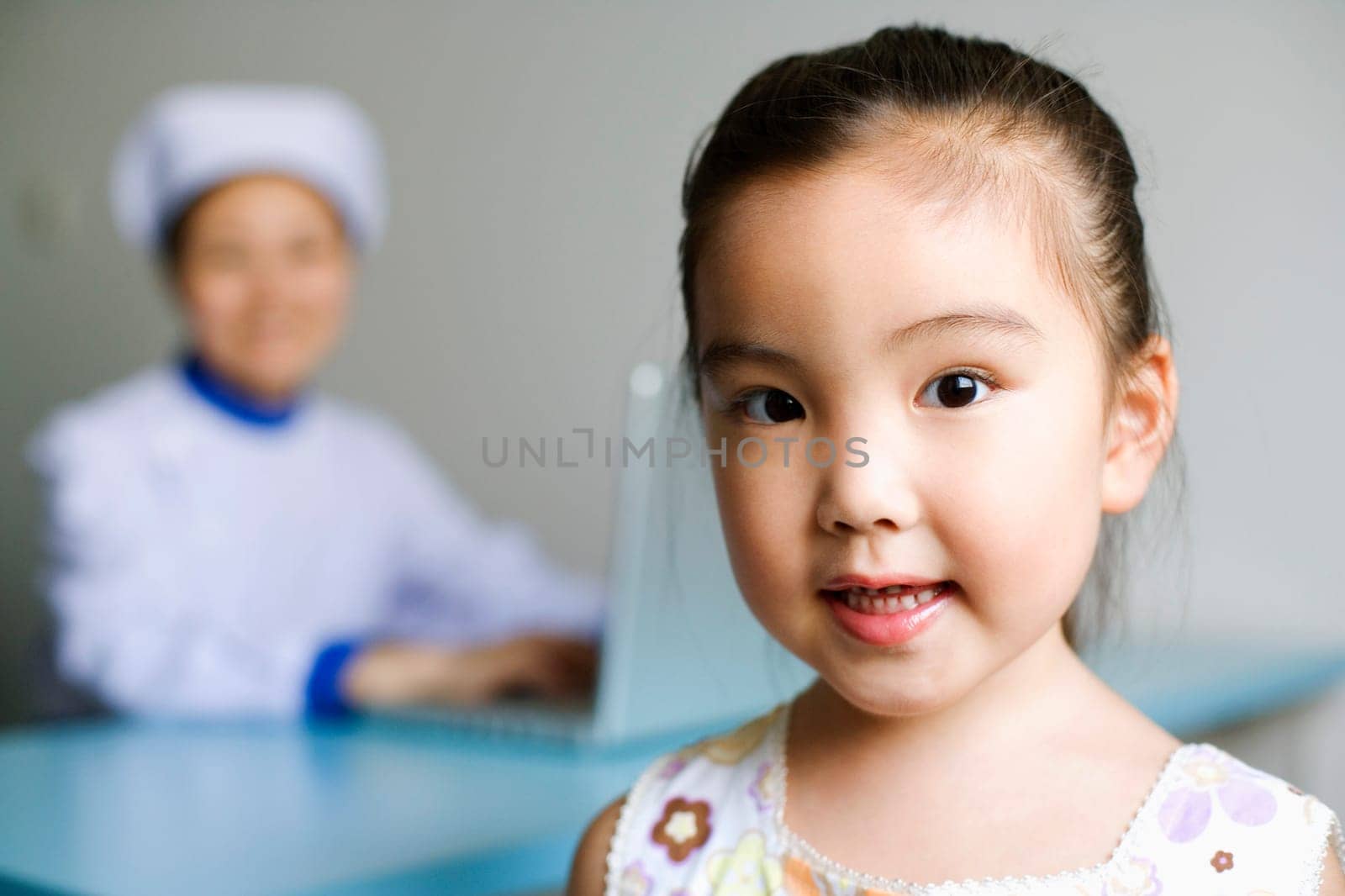 Portrait of a girl and a nurse working on a laptop in the background