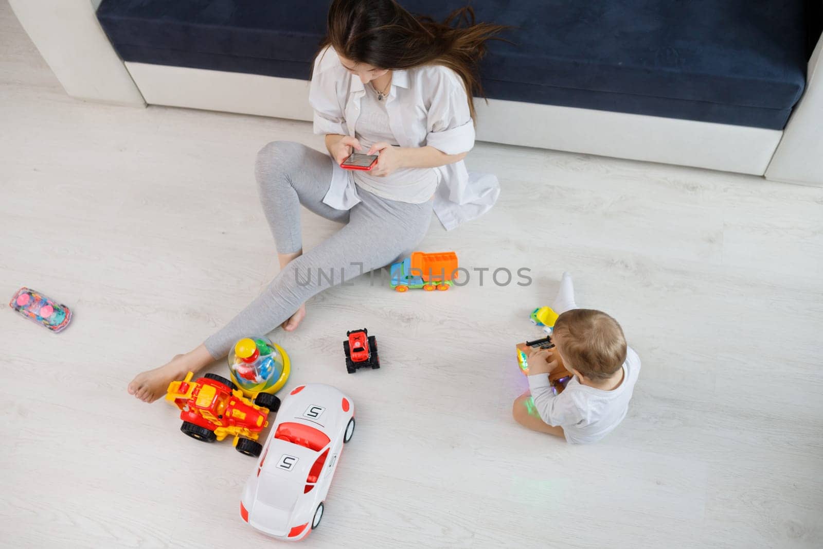 Young woman ignore her kid and looking at their mobile phones. Top view