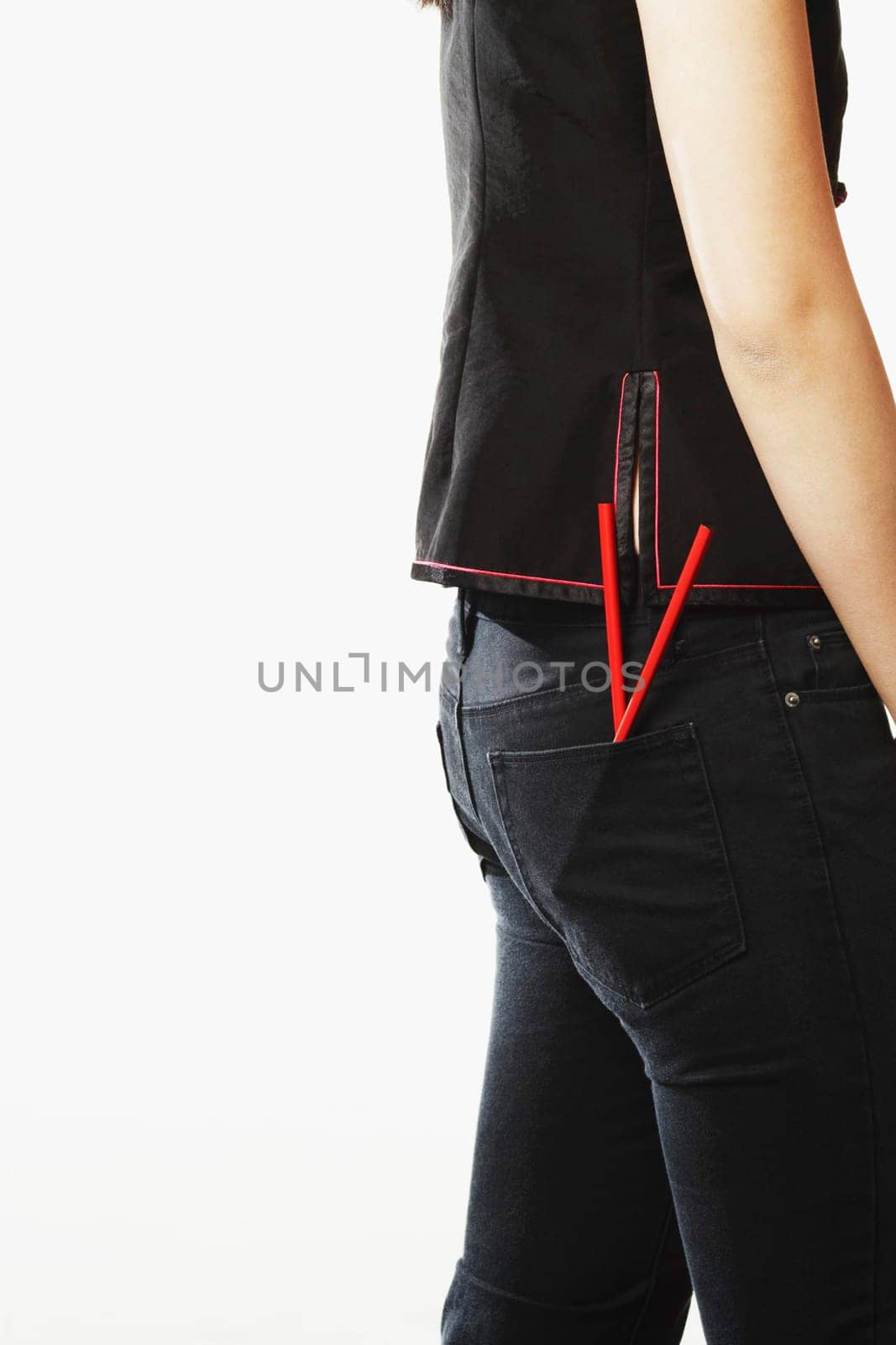 Mid section view of a young woman with chopsticks in her pockets