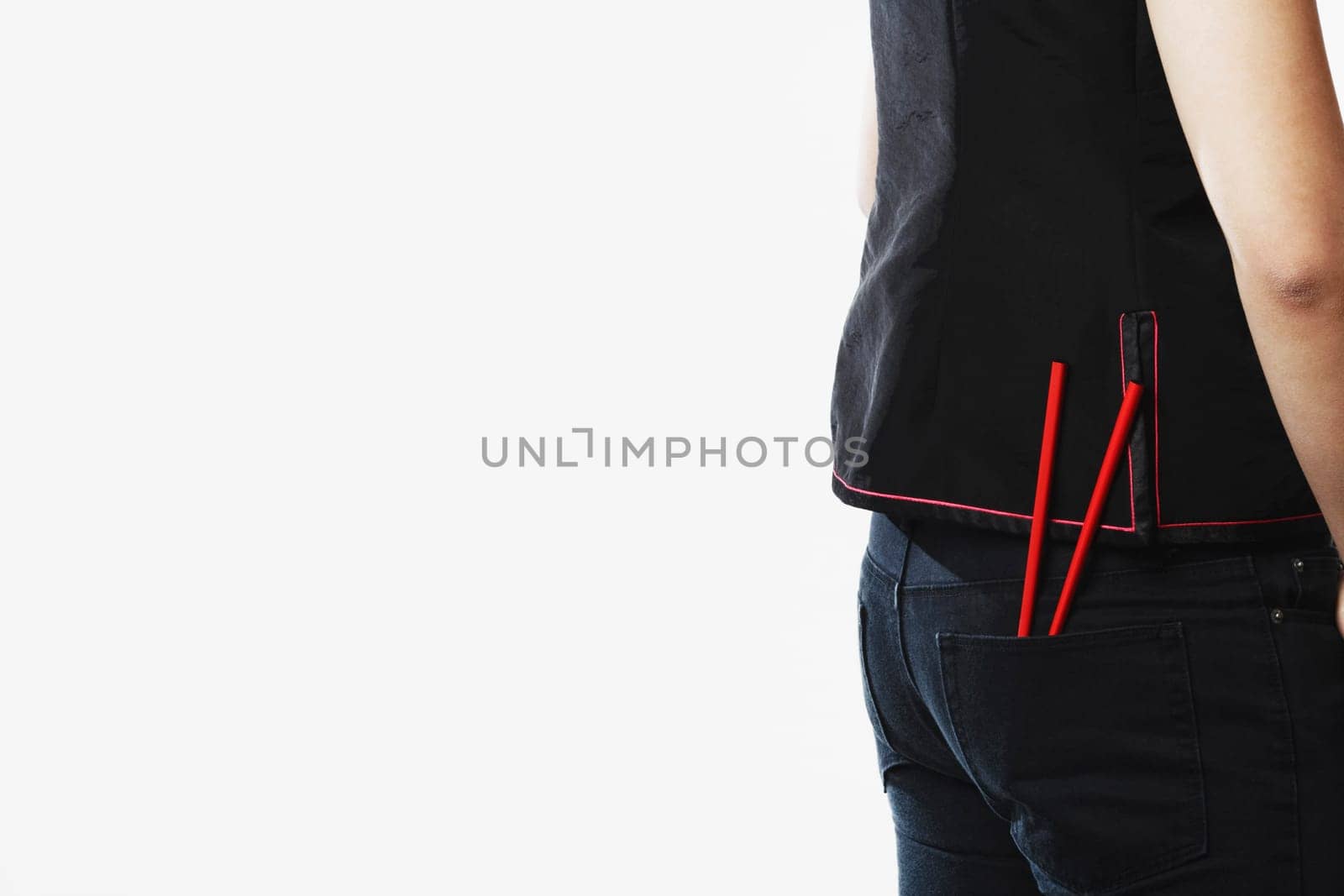 Mid section view of a young woman with chopsticks in her pockets