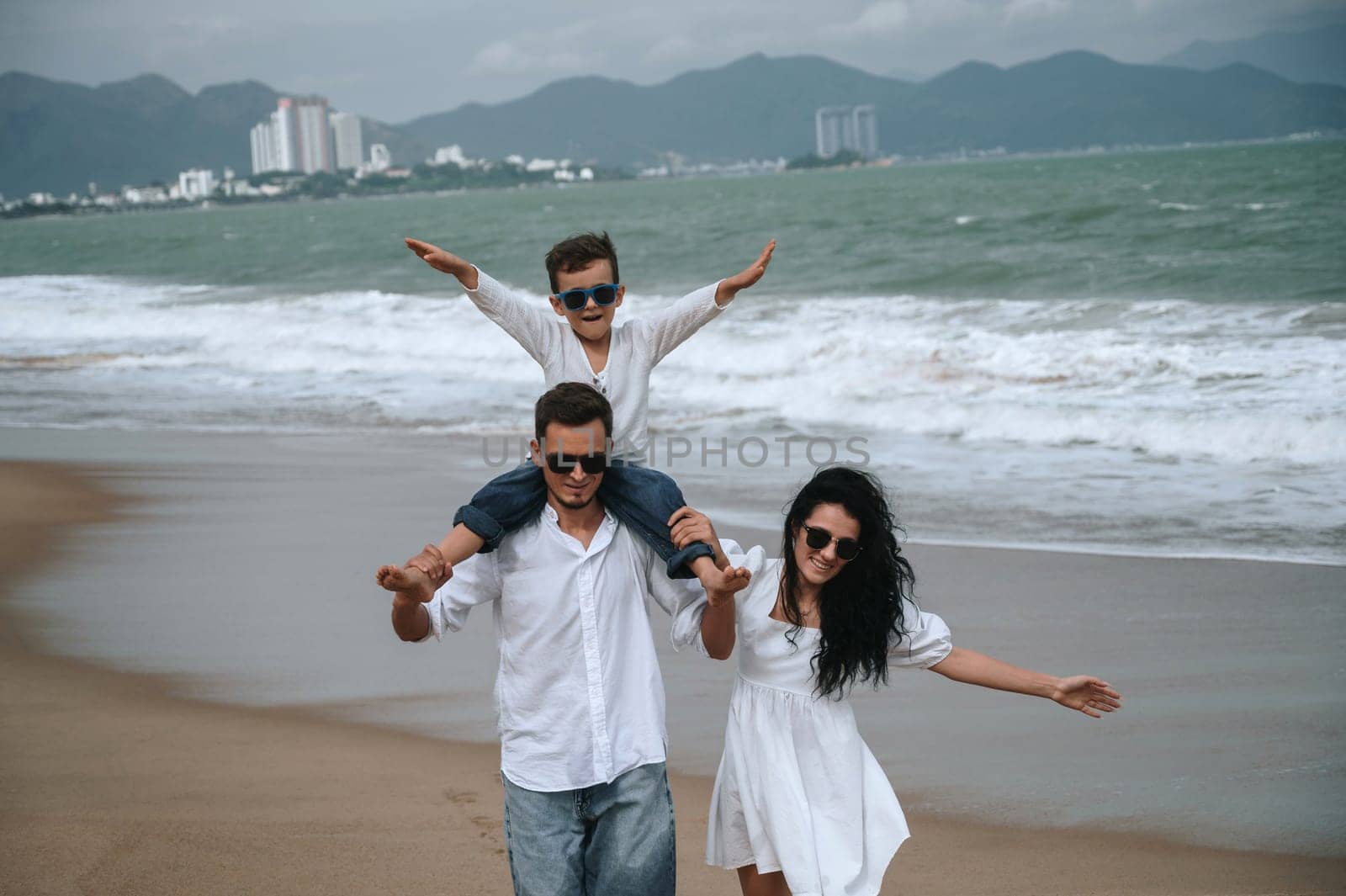 happy family parents with a child son on the beach in the sea on summer
