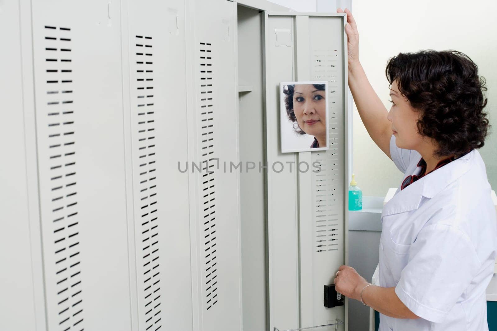Side profile of a female looking at a mirror on the door of a locker