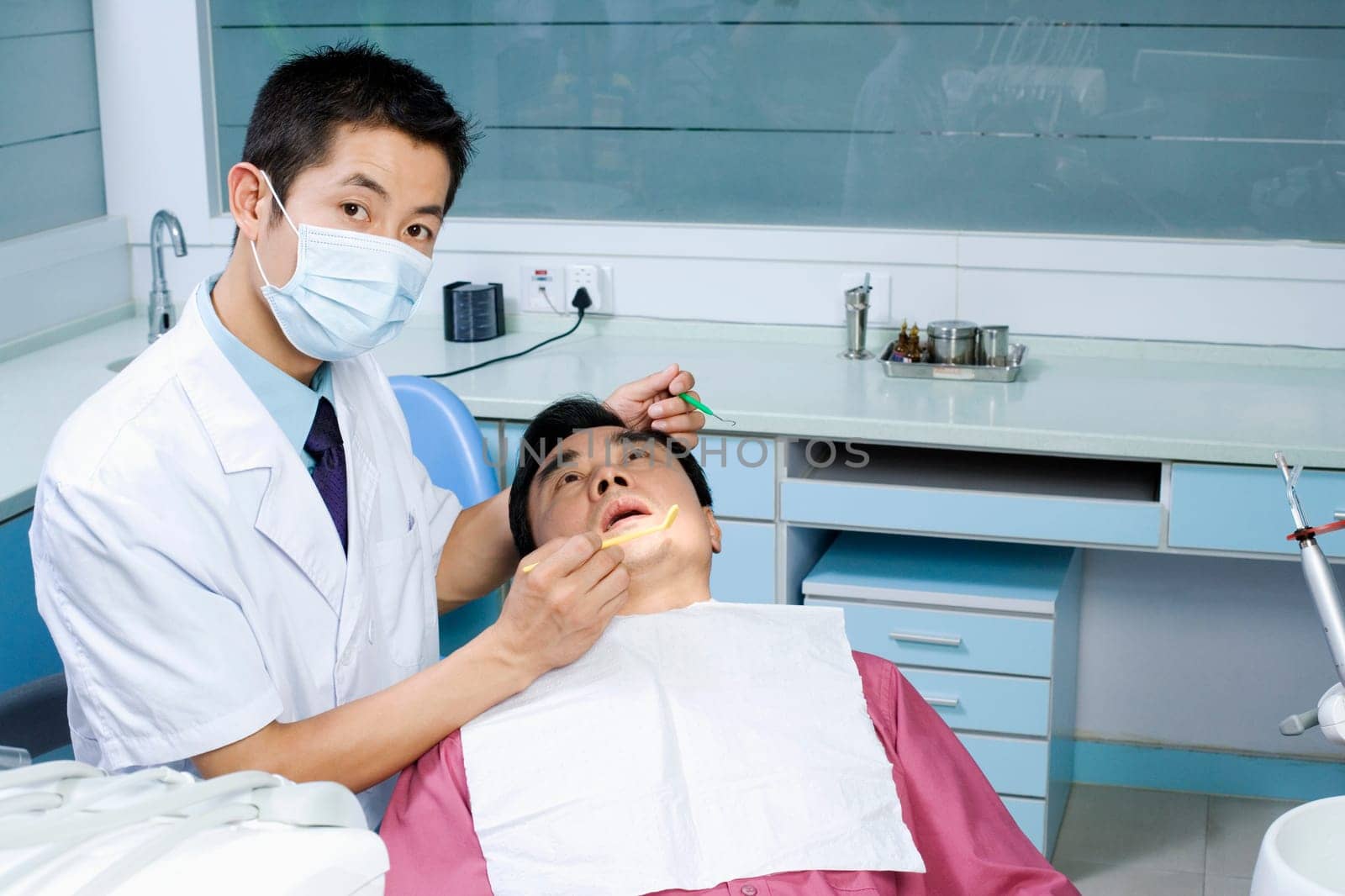 Close-up of a male dentist examining a male patient