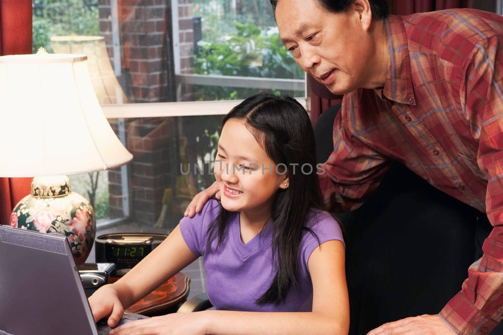 Close-up of a girl using a laptop with her father behind her