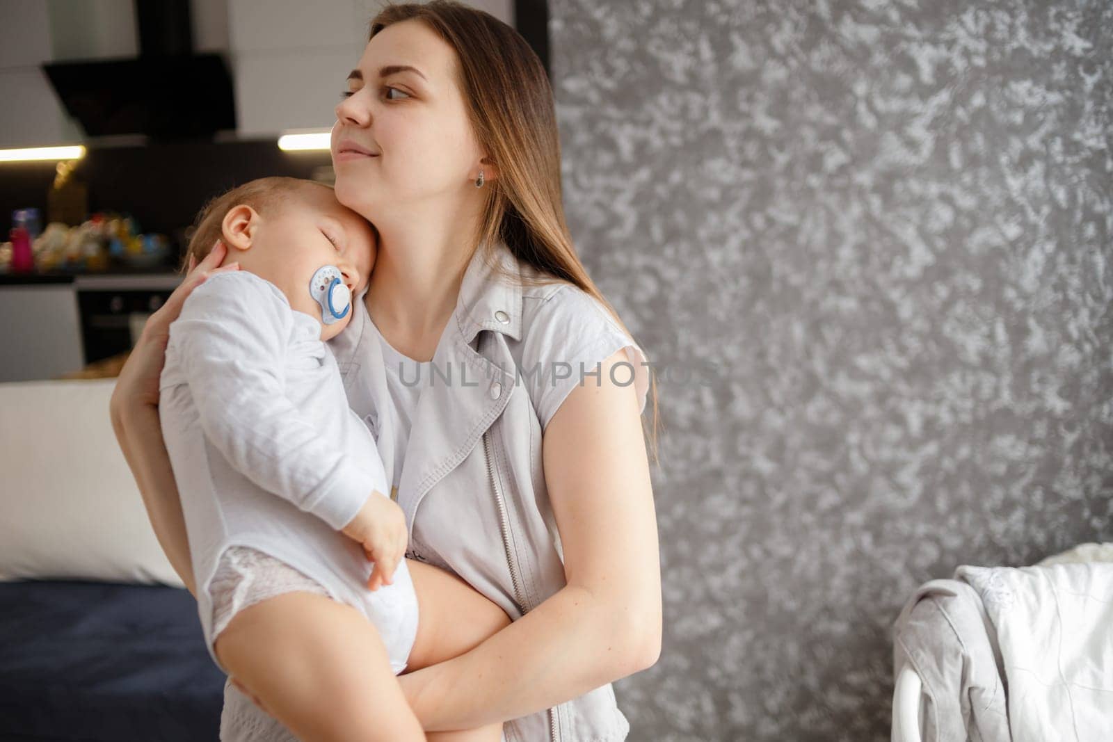 Infant baby falled asleep in mother arms. Home photo. Lifestyle portrait.