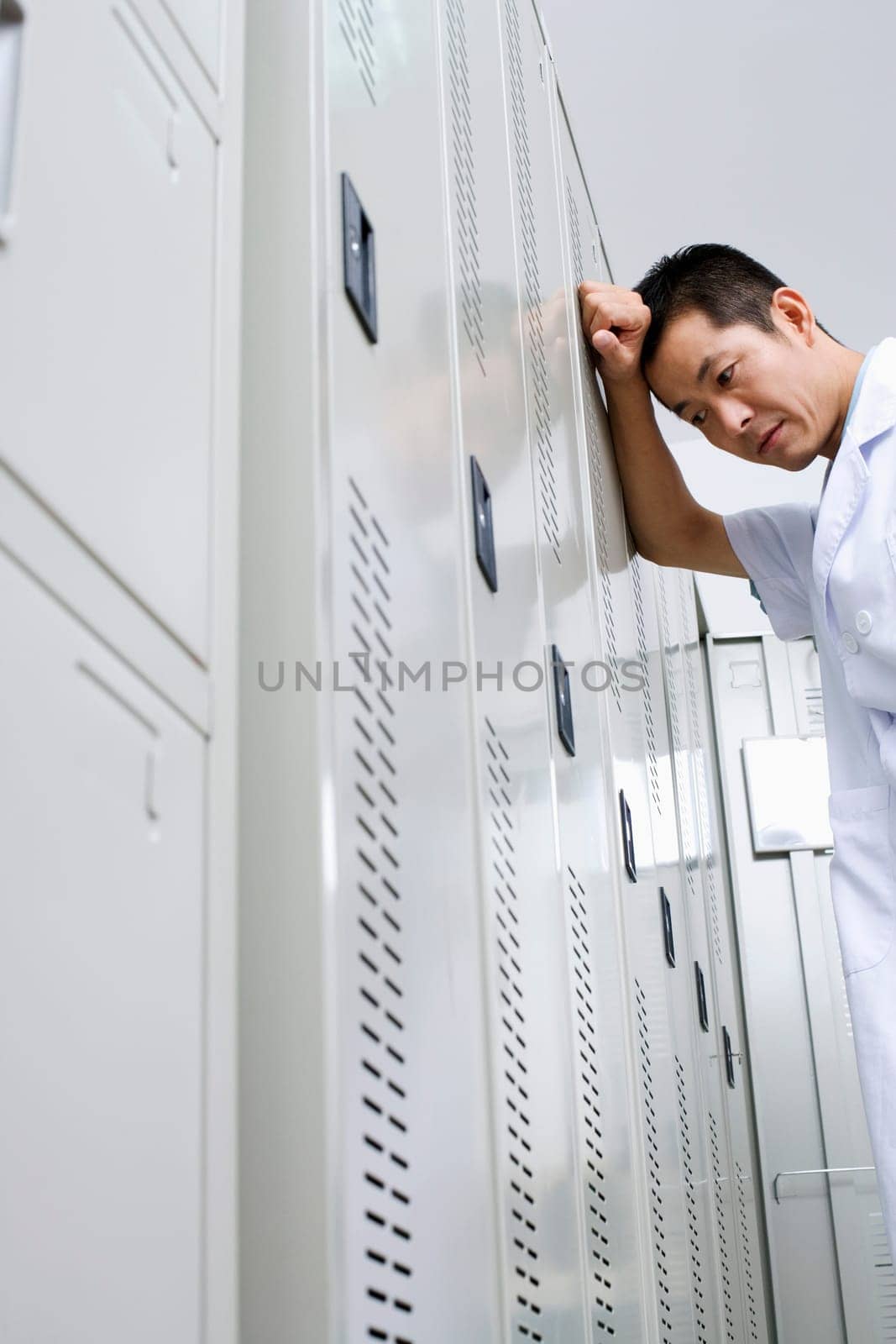 Low angle view of a doctor leaning against a locker
