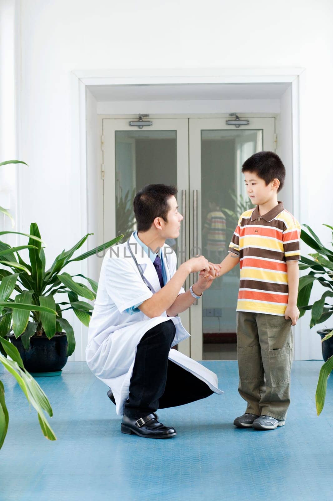 Male doctor crouching with a boy standing beside him