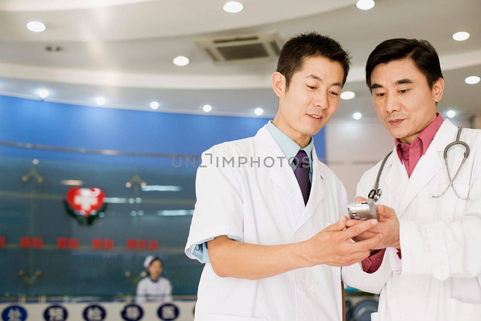Close-up of two male doctors looking at a personal data assistant