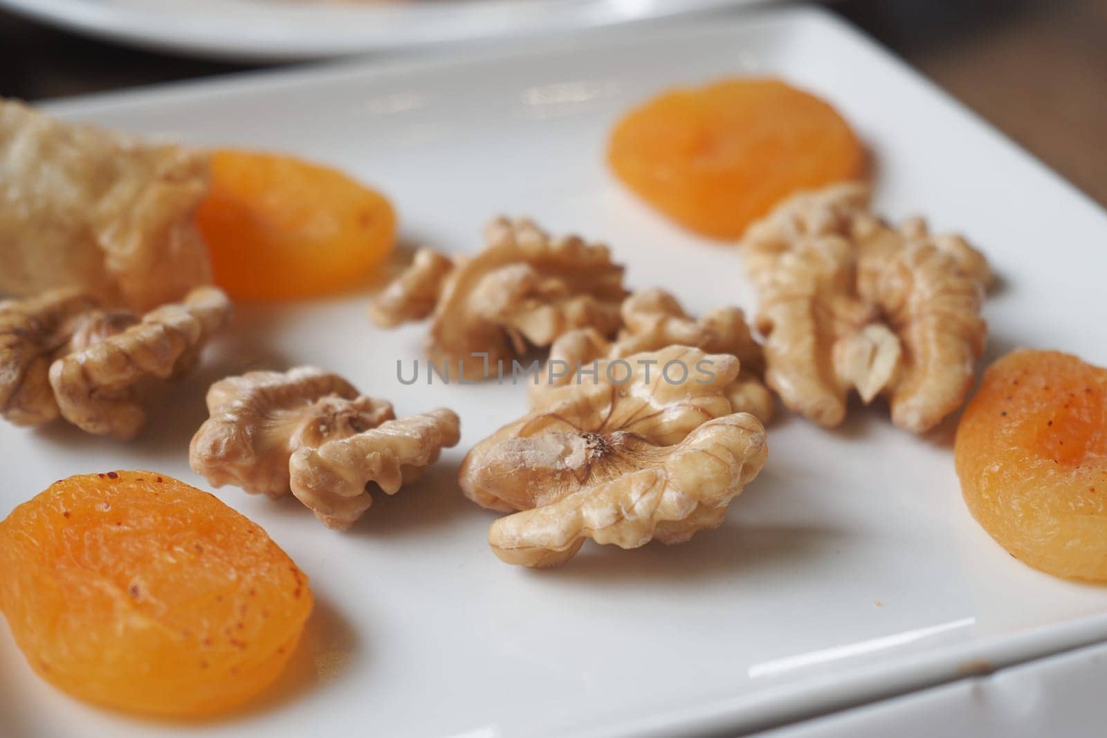 Dried apricots and walnuts are arranged attractively on a plate.