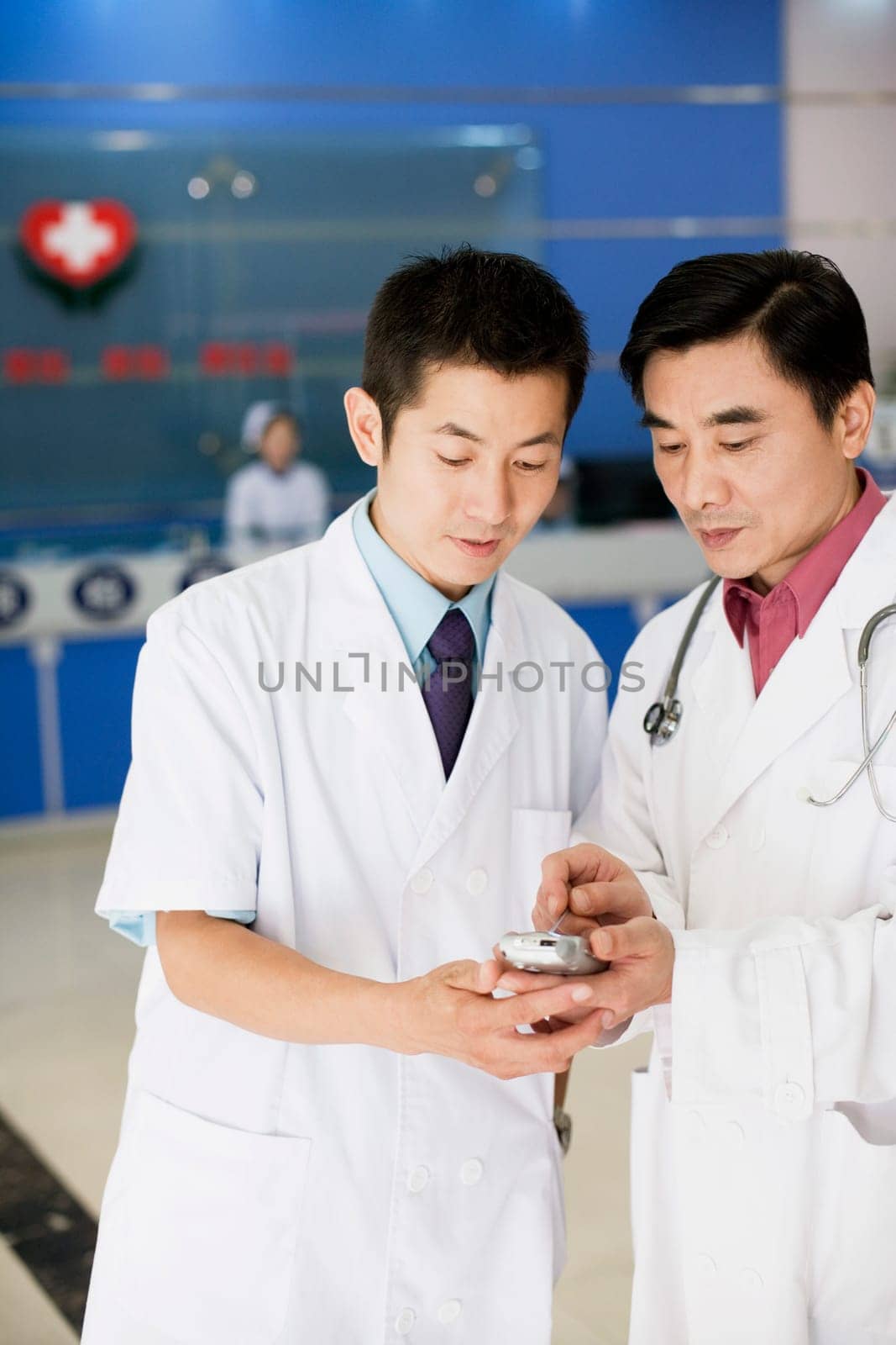 Close-up of two male doctors looking at a personal data assistant