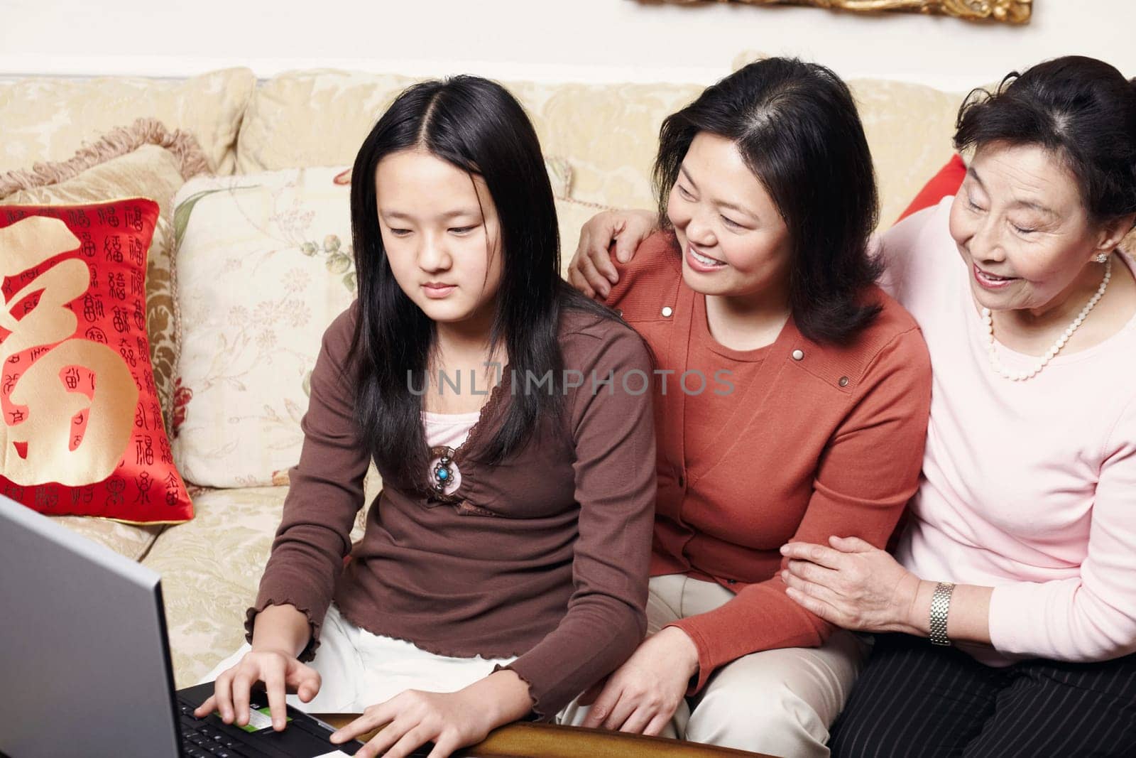 Close-up of a daughter using a laptop with her mother and her grandmother sitting beside her
