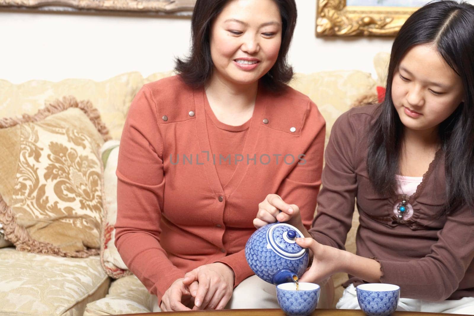Close-up of a girl pouring tea for her mother