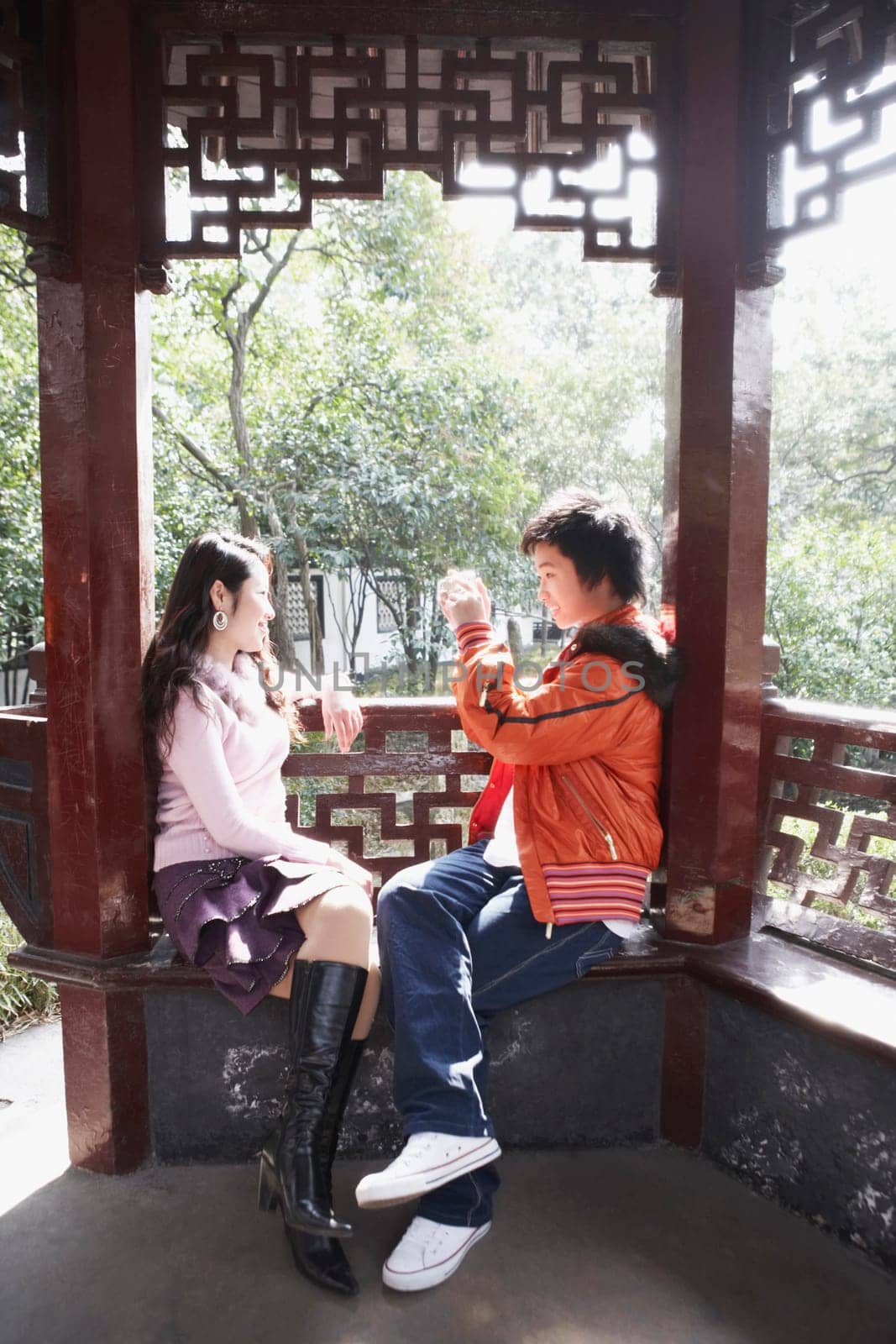 Side profile of a teenage boy taking a photograph of a young woman with a video camera