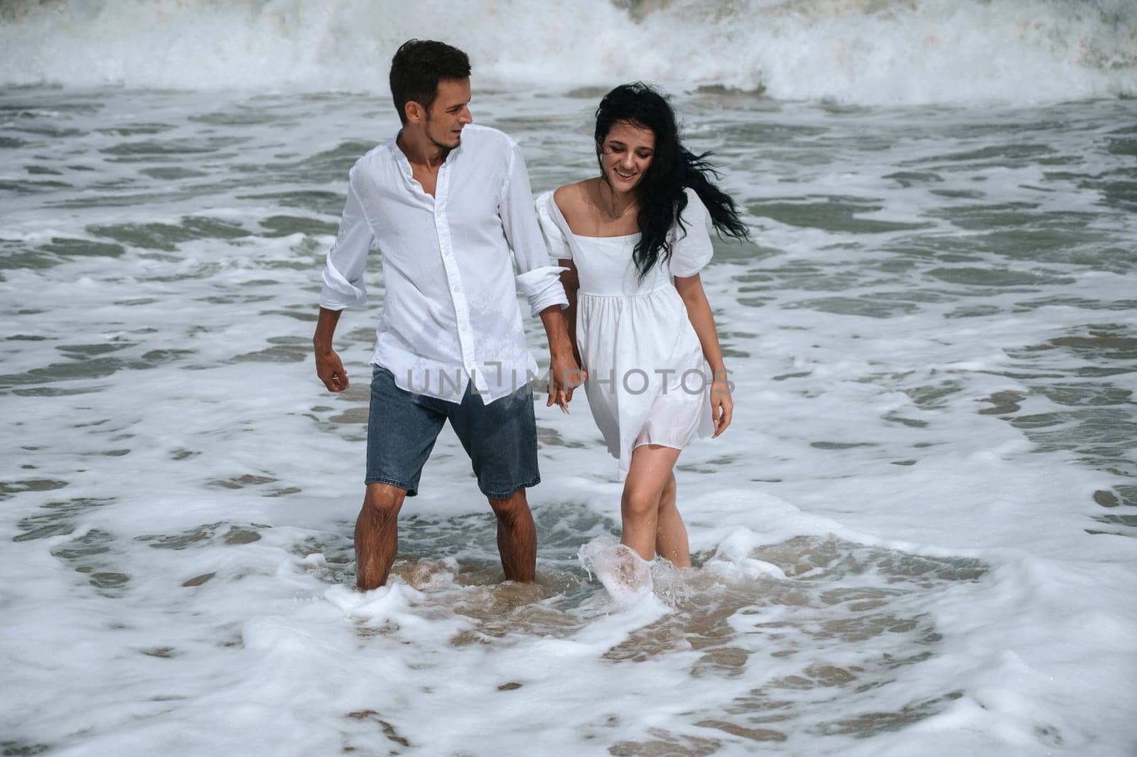 Happy young couple in love on the beach by the sea in summer