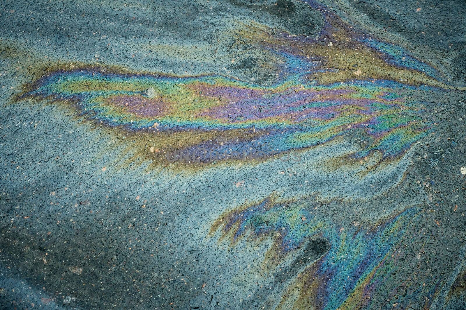 Colorful gasoline patch producing a striking rainbow sheen on the black asphalt road surface