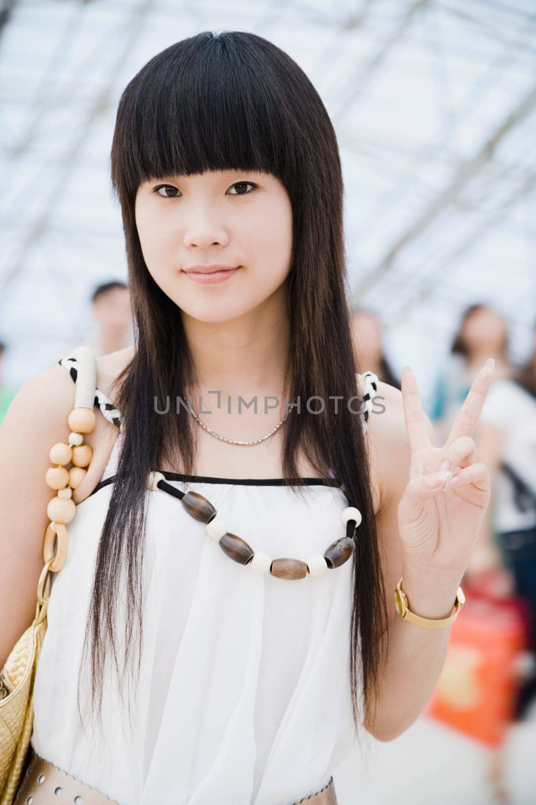 Portrait of a young woman standing in a corridor and making a peace sign