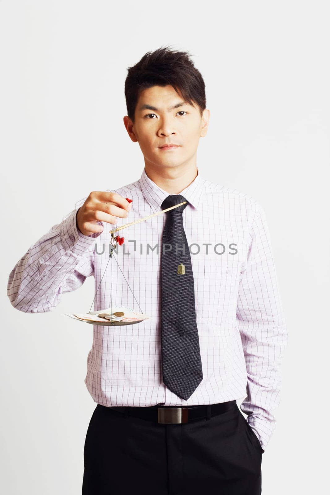 Portrait of a businessman weighing paper currency with coins on a weighing scale